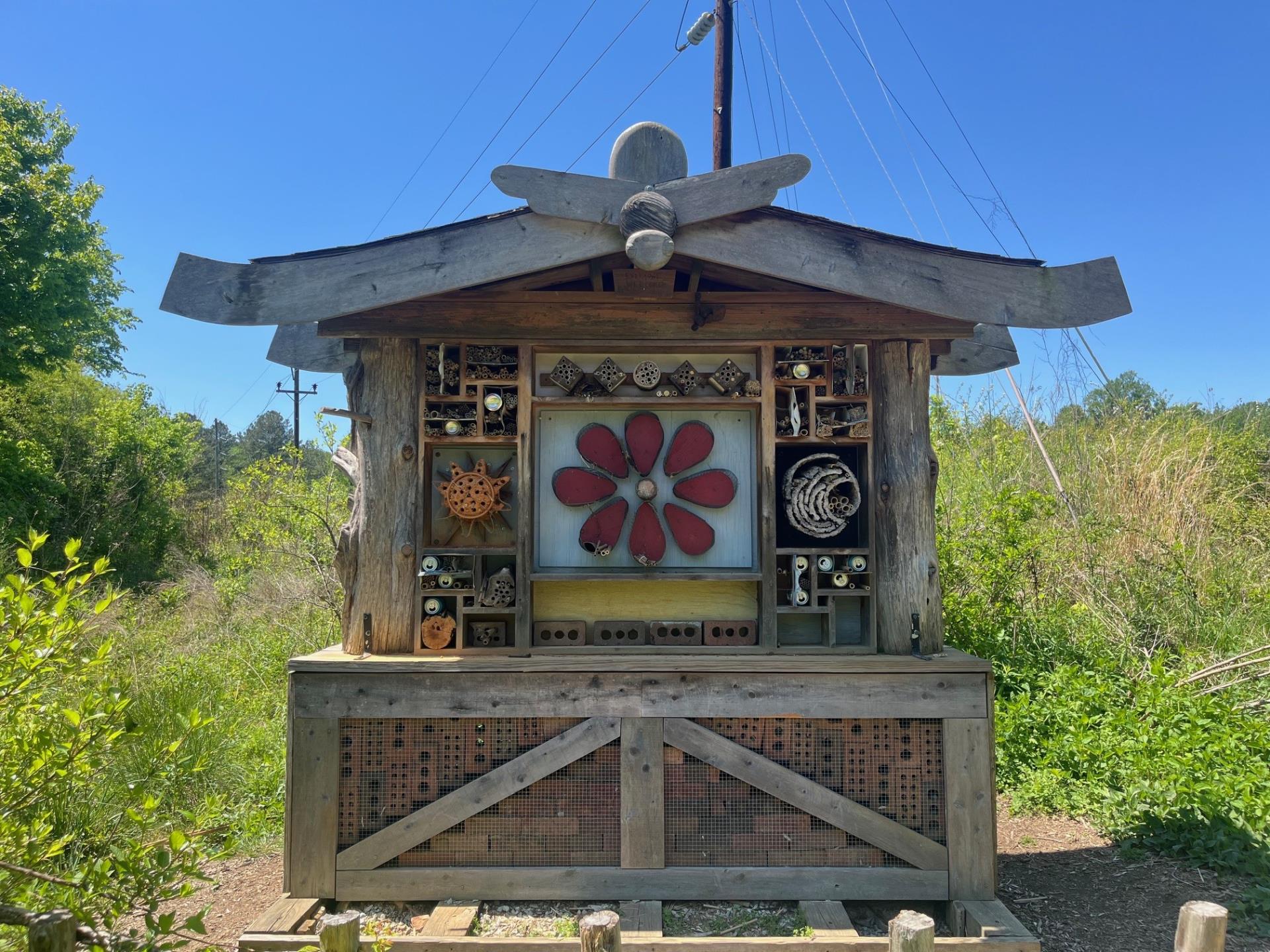 Gold Park Bee Hotel on a beautiful day. The pollinator garden in the background is very green.