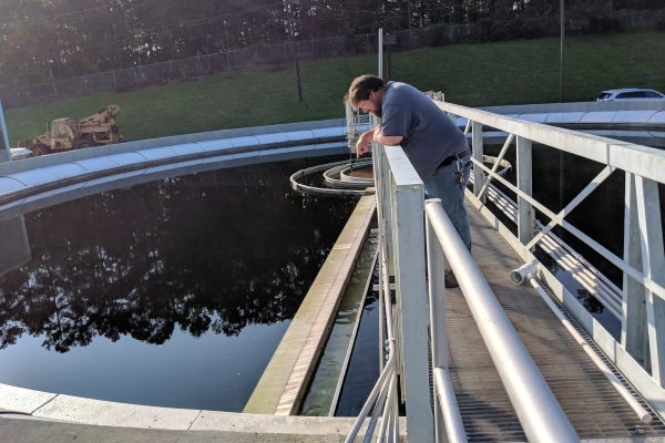 An employee inspects a clarification tank used to skim the surface of treated used water and remove debris..