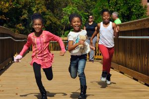 Three young girls run on greenway bridge