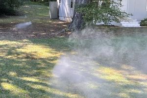 White vapor rising from lawn in front of white house