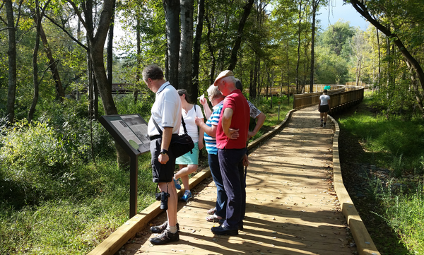 People reading a sign along the Riverwalk.