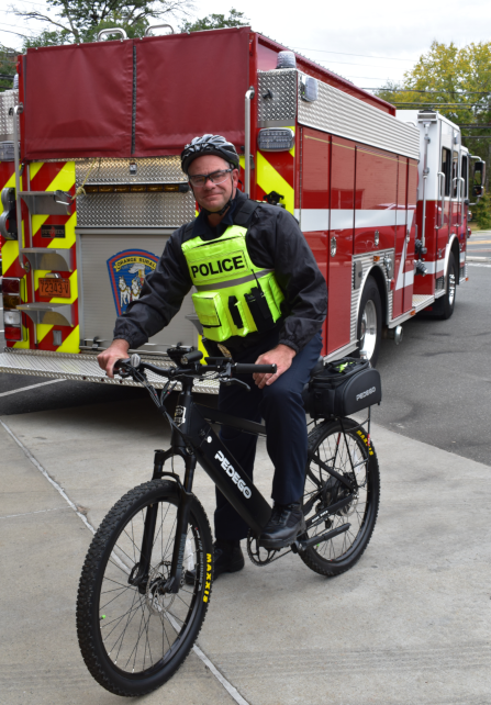 Hillsborough police chief on bike with fire truck in background